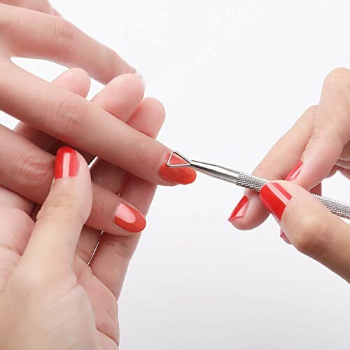 Close-up of hands using a cuticle pusher during a manicure.